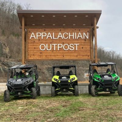 a green truck parked in front of a motorcycle